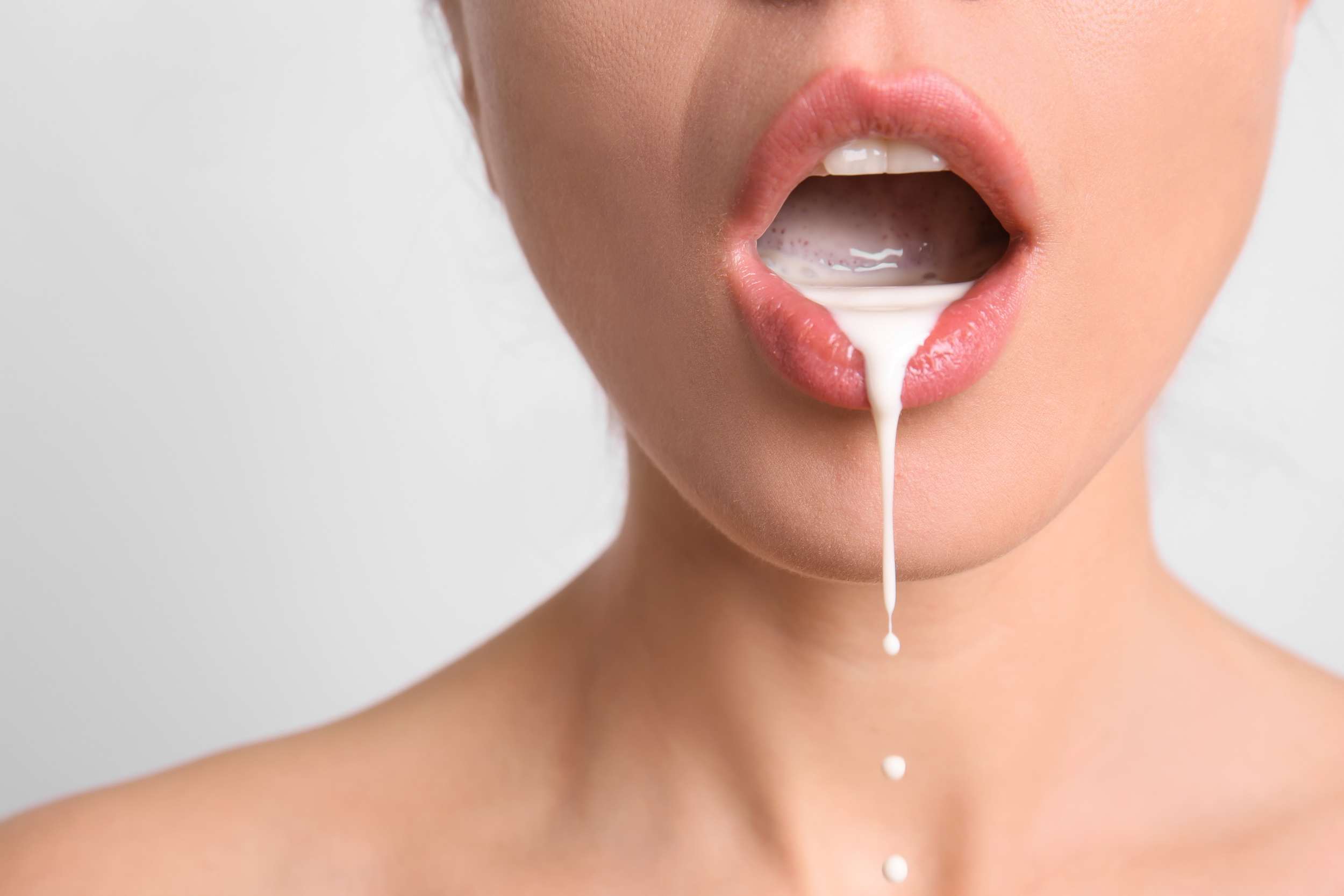 Une bouche de femme sensuelle avec du lait qui coule. C'est de la suggestion pour le sperme de l'homme.