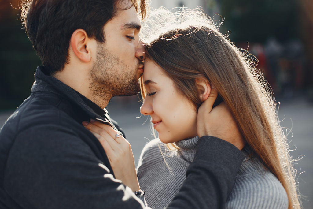 Un couple dans la rue. L'homme embrasse le front de sa compagne. Elle semble amoureuse.