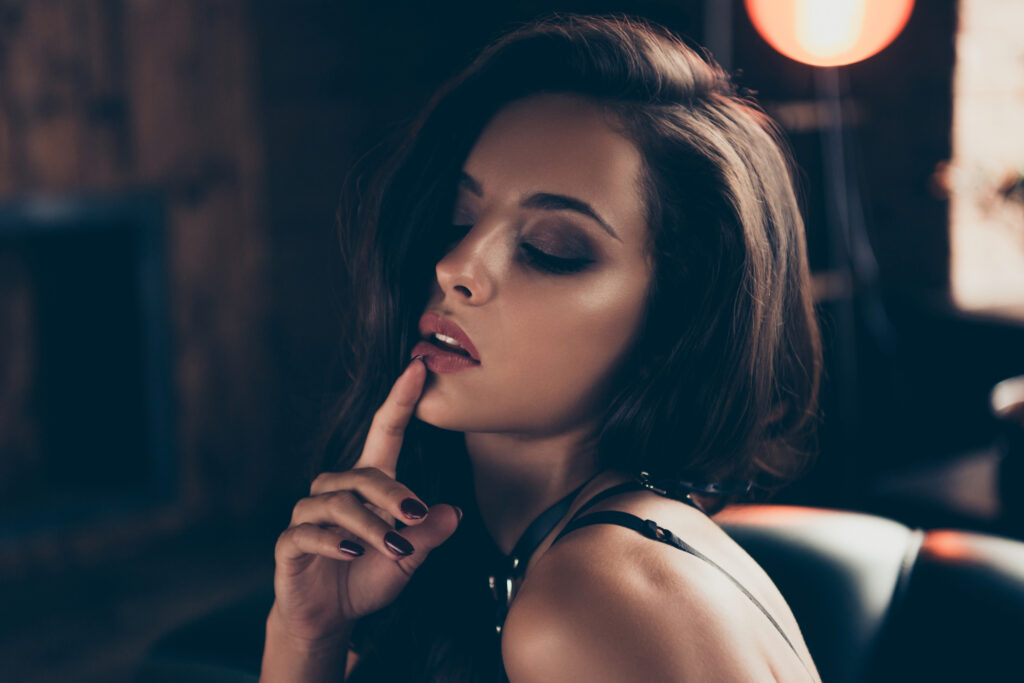 Une femme sensuelle qui met son index sur sa bouche pour mimer le silence.